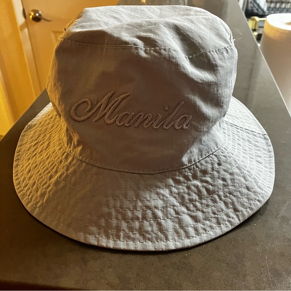 Gray adult size bucket hat with the word Manila embroidered